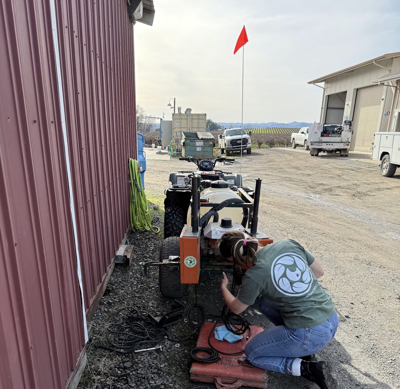 A Cropsy engineer kneeling beside a shed to service a scanner unit on its mount