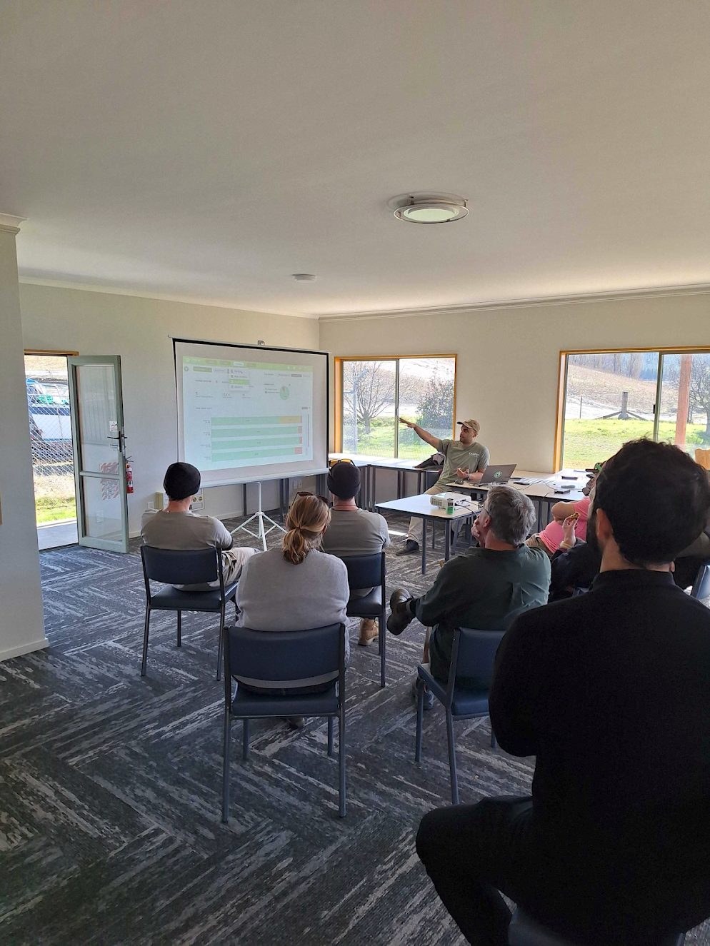 A room of growers watching a Cropsy presentation, vineyard data on the projected screen