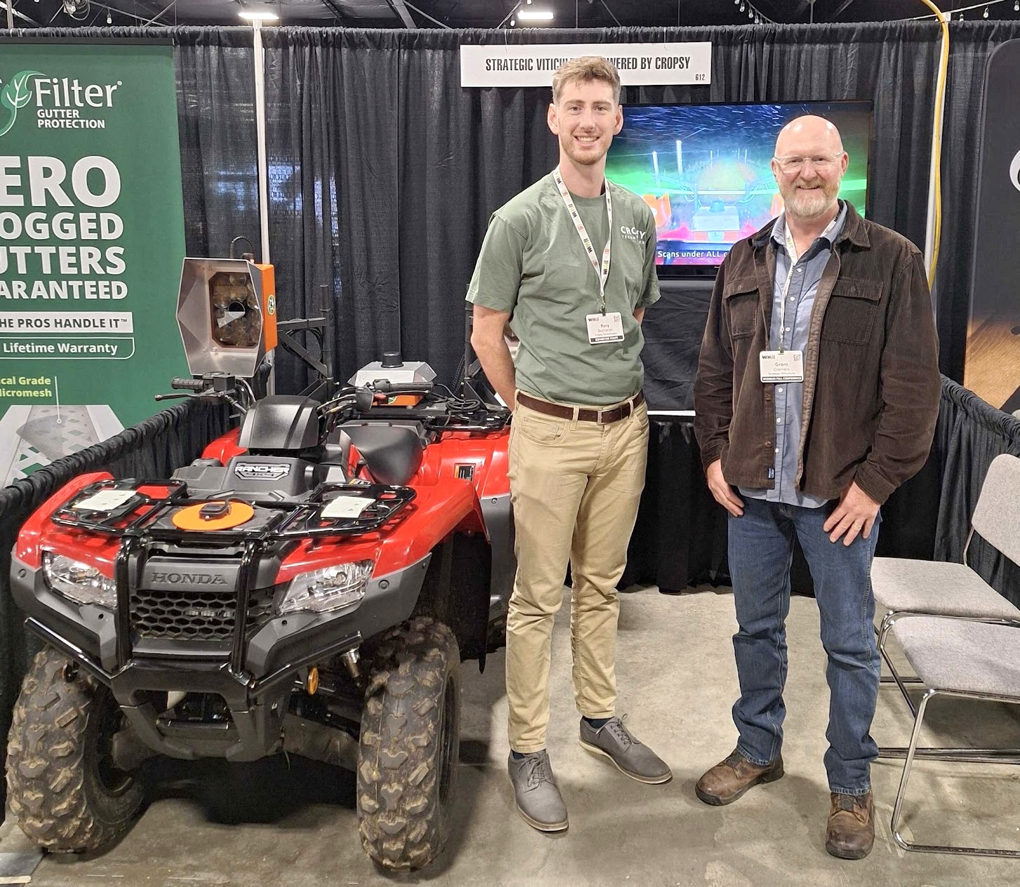 A quad bike rigged with a Cropsy scanner mount on a trade-show stand, two people beside it under a Strategic Viticulture powered by Cropsy sign