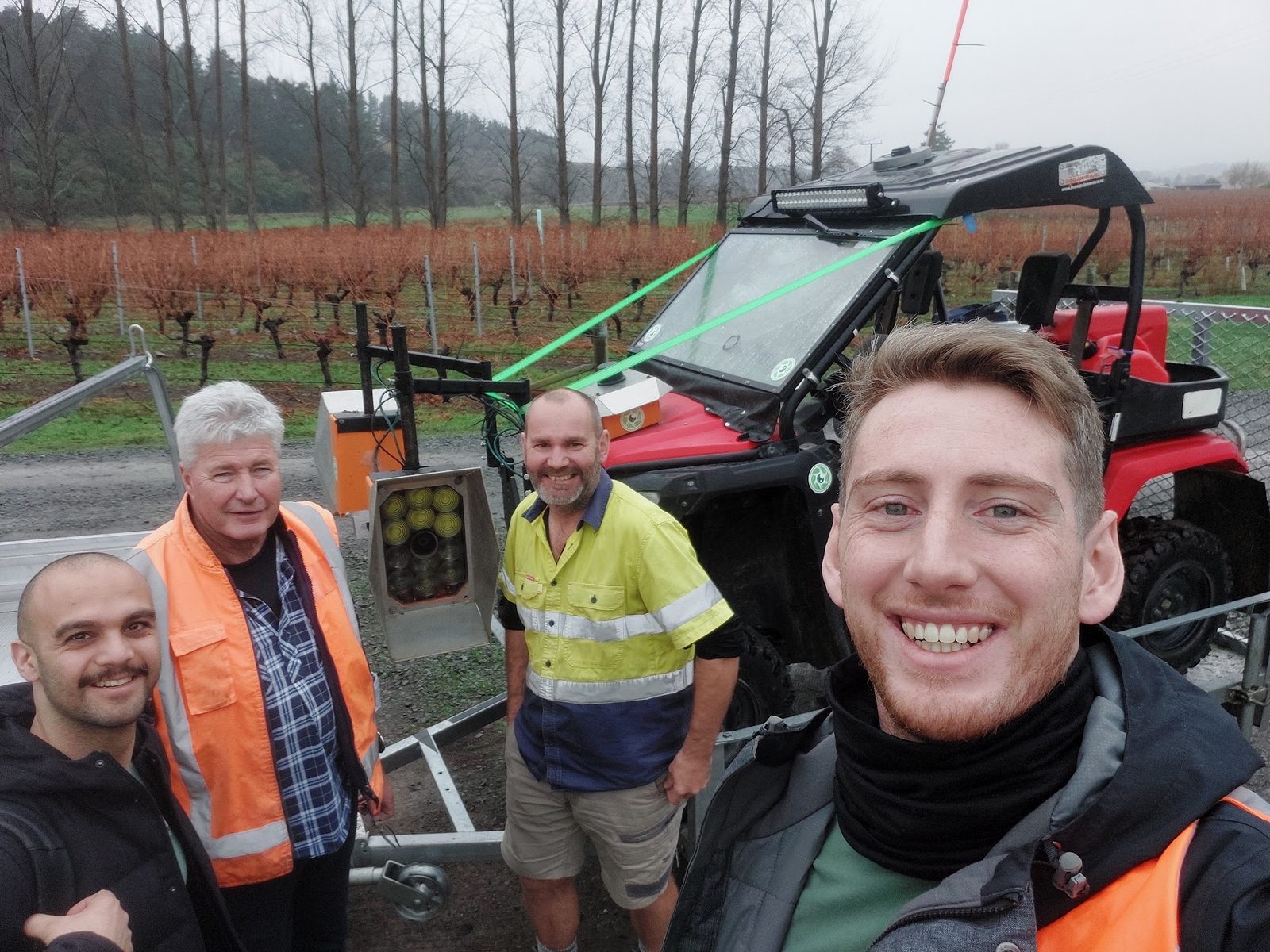 Cropsy staff and vineyard crew together in a misty winter vineyard, beside an autonomous vehicle platform and a quad bike