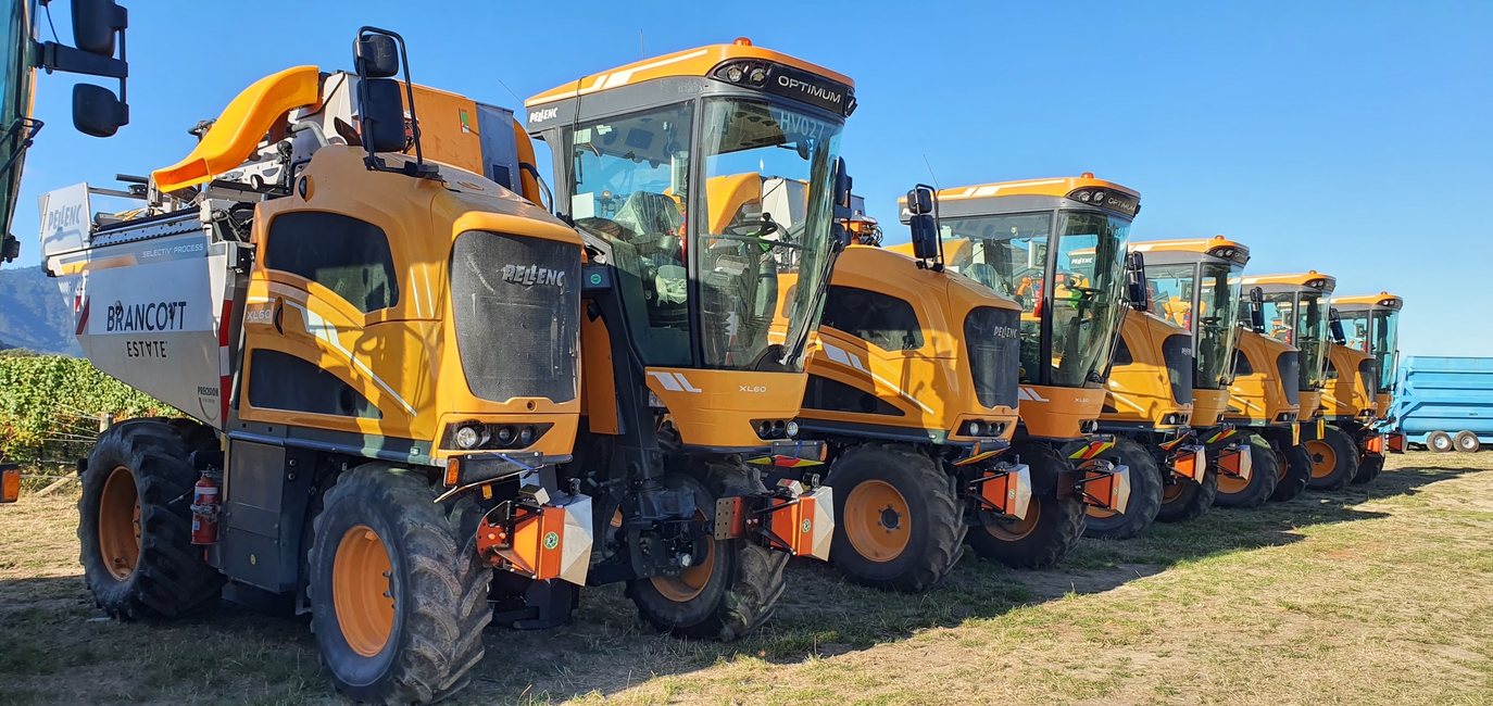 A line of yellow Pellenc grape harvesters, each fitted with orange Cropsy scanner units
